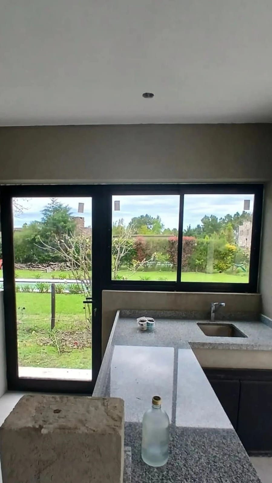 Cocina con corrediza y puerta negras que miran a un jardín con pileta