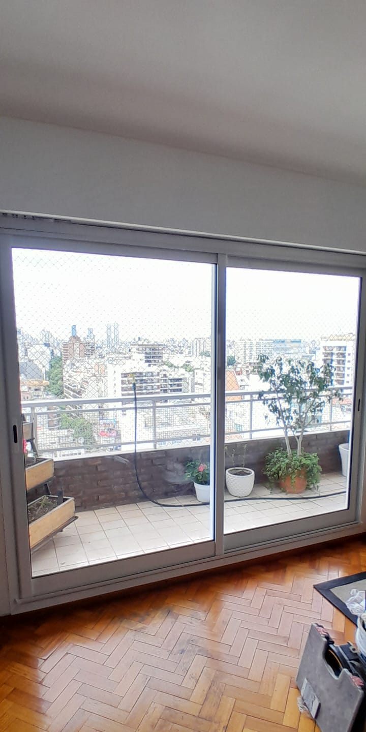 Corrediza blanca de dos hojas con vista a la ciudad desde un balcón