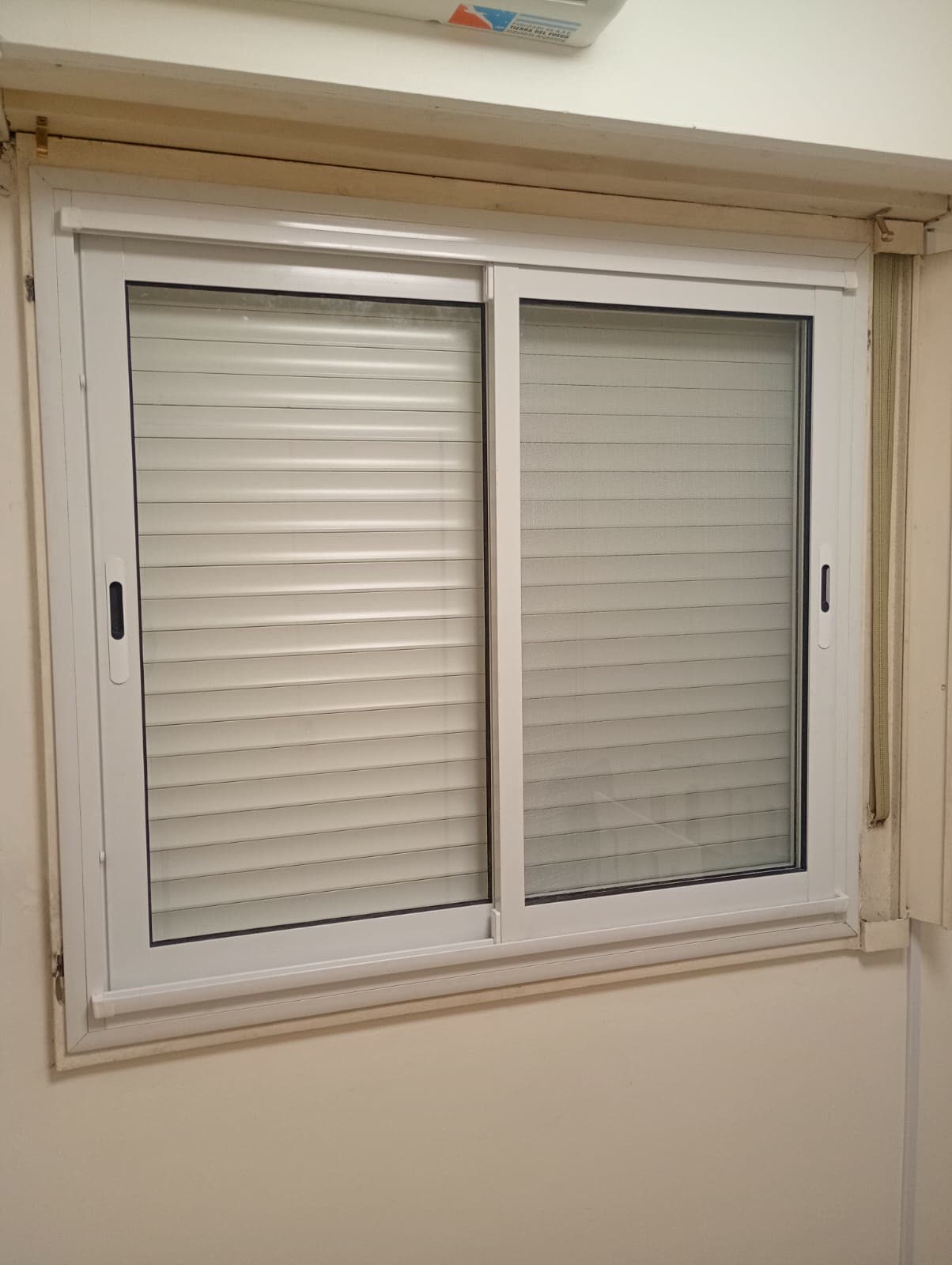 Corrediza blanca con cortina de enrollar en un dormitorio