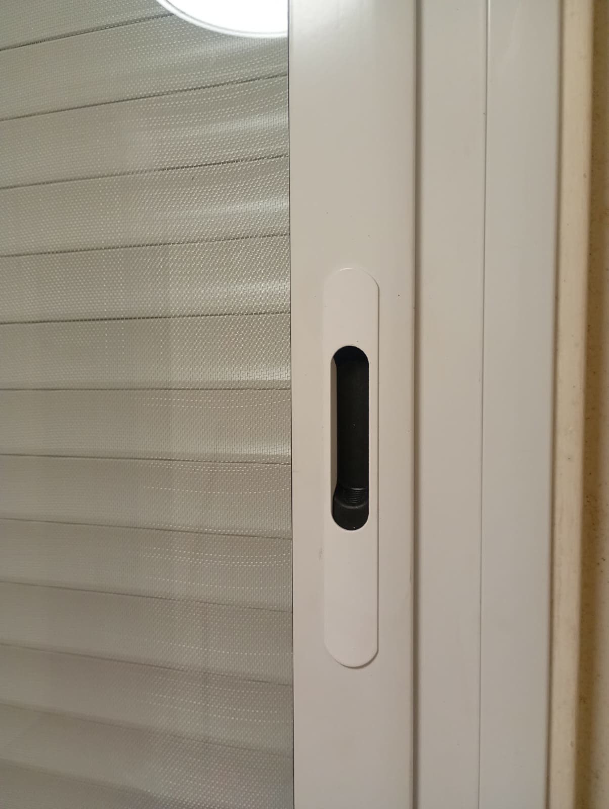 Detalle del tirador de una corrediza blanca con persiana