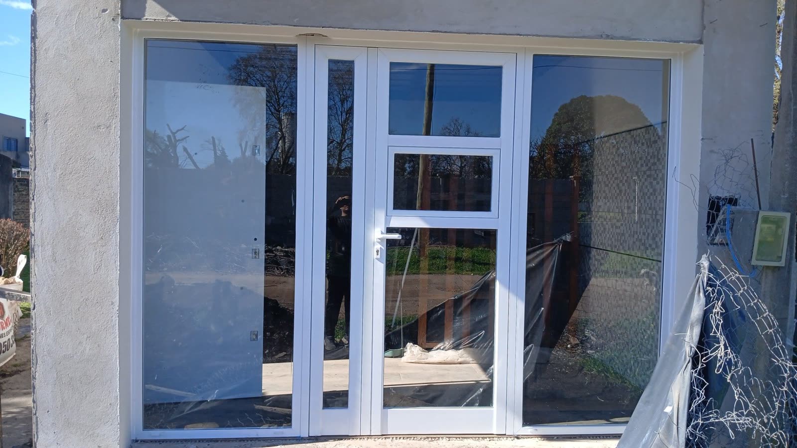 Frente de aluminio blanco recién colocado en una obra, con puerta y paños fijos