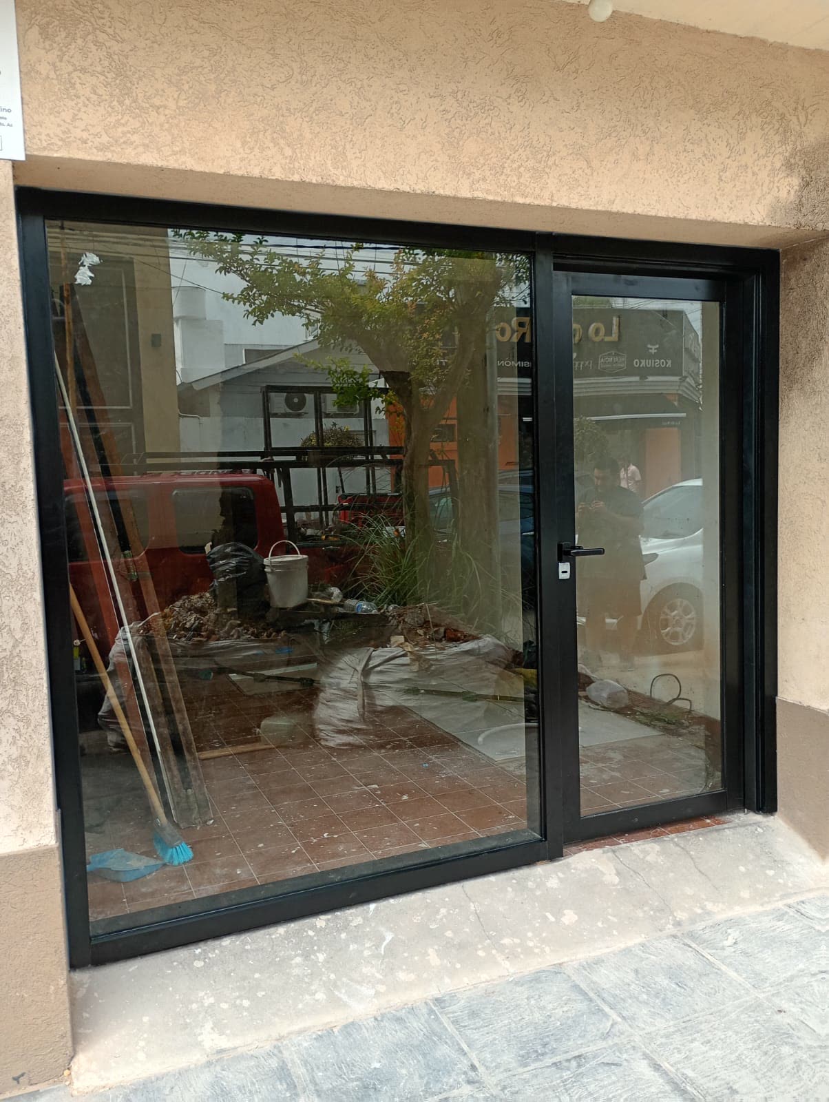 Frente de local con puerta y paño fijo de aluminio negro