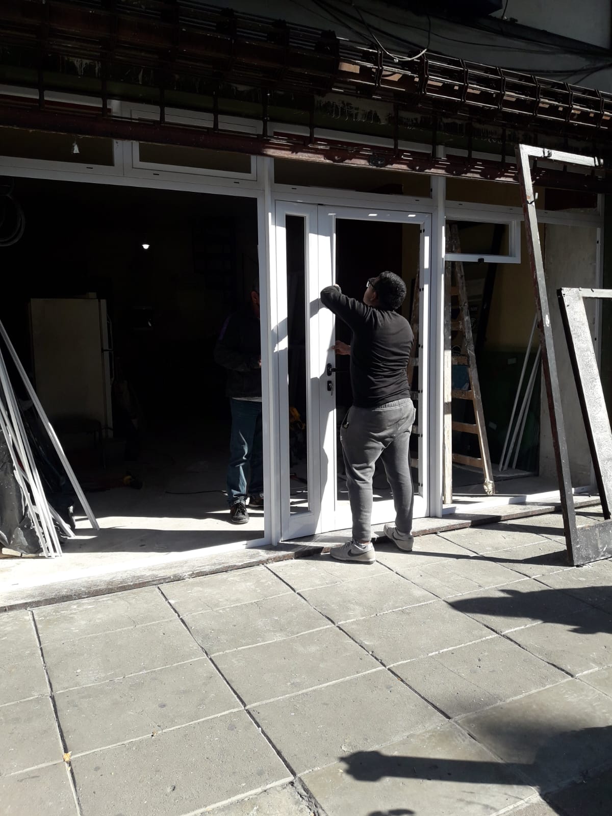 Colocación de una puerta de aluminio blanca en un frente comercial