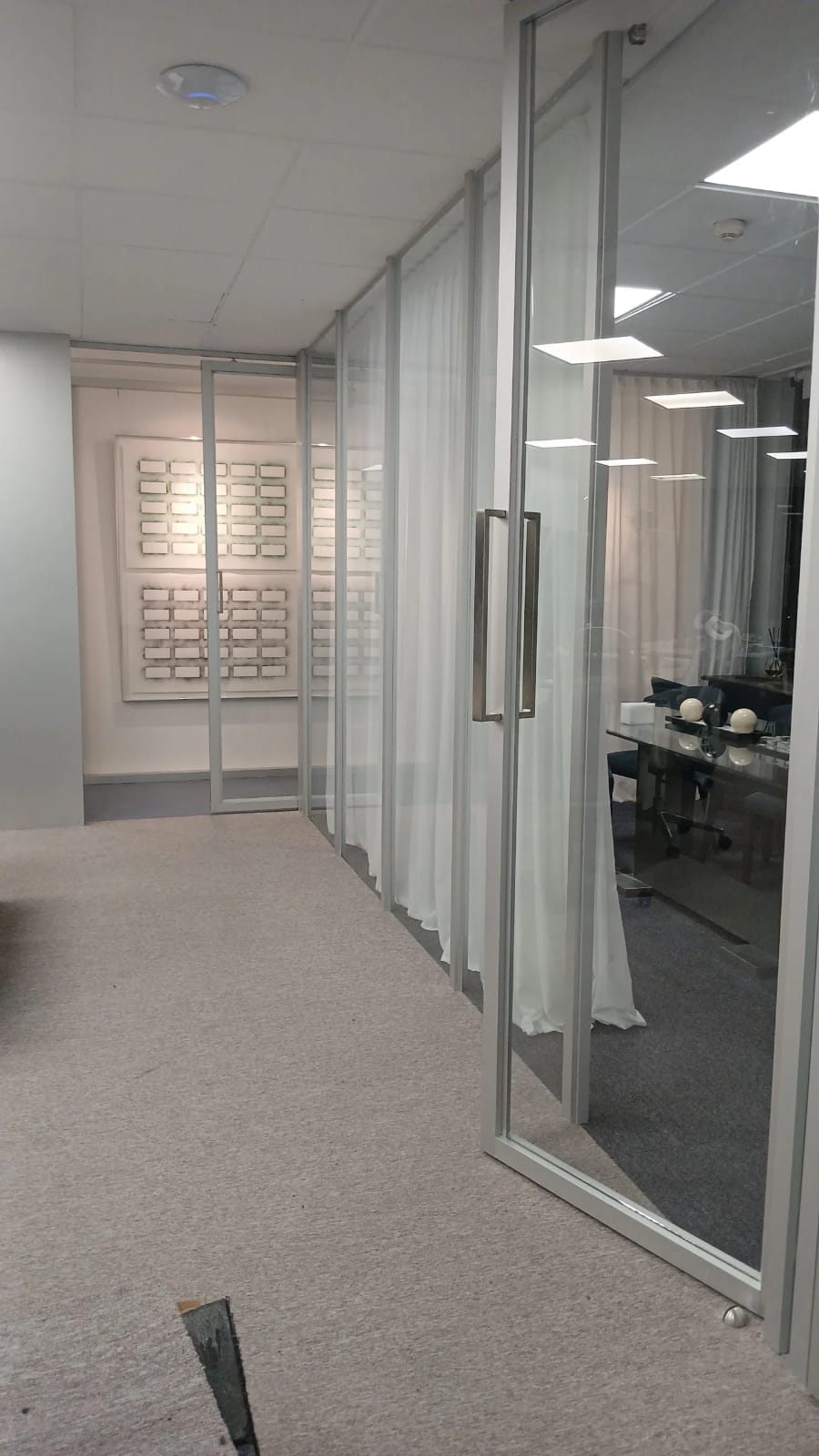 Oficina con divisiones y puertas de vidrio con perfiles de aluminio