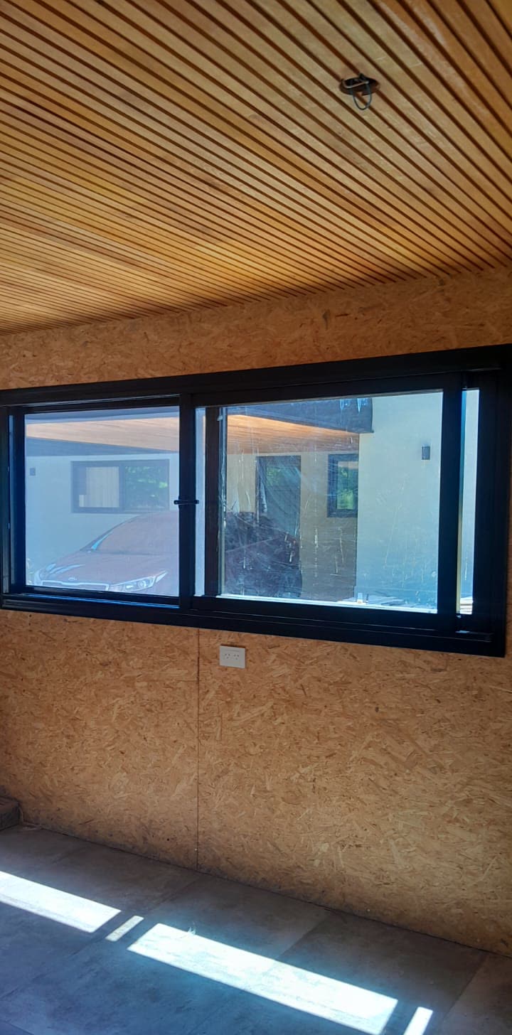Ventanas negras corredizas en una casa con techo de madera